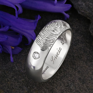 A White Gold Wedding Ring with an engraved fingerprint on the outer surface | Set with two diamonds that frame the fingerprint | Engraved with two names on the inside of the ring | Hand engraving | Mens 6mm wide, comfort court profile ring | Custom personalised wedding jewellery | Sophia Alexander Fingerprint Jewellery | Handmade in Suffolk UK