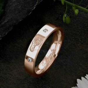 A Rose Gold Wedding Ring with an engraved baby footprint on the outer surface | Set with two diamonds that frame the footprint | Engraved with the name Elijah on the inside of the ring | Hand engraving | Ladies slim 4mm wide, comfort flat-court profile ring | Custom personalised wedding jewellery | Sophia Alexander Fingerprint Jewellery | Handmade in Suffolk UK