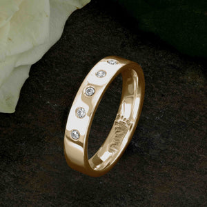 An 18ct Gold Wedding Ring with an engraved baby footprint on the inside surface | Set with five beautiful diamonds on the outer surface of the ring | Hand engraving | Ladies slim 4mm wide, comfort flat-court profile ring | Custom personalised wedding jewellery | Sophia Alexander Fingerprint Jewellery | Handmade in Suffolk UK