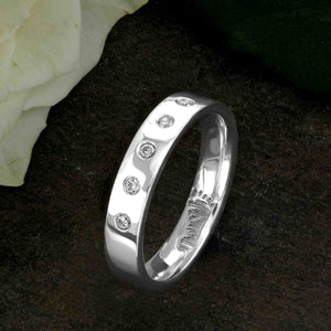 An 18ct White Gold Wedding Ring with an engraved baby footprint on the inside surface | Set with five beautiful diamonds on the outer surface of the ring | Hand engraving | Ladies slim 4mm wide, comfort flat-court profile ring | Custom personalised wedding jewellery | Sophia Alexander Fingerprint Jewellery | Handmade in Suffolk UK
