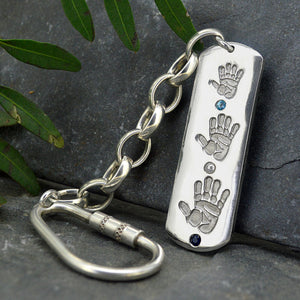 Large dog tag style long Pendant in solid silver with three children's handprints | Set with aquamarine, pearl and sapphire gemstones | Birthstones for March, June and September | Shown on a keyring with a chain | Personalised Gift | Sophia Alexander Fingerprint Jewellery | Handmade in Suffolk UK
