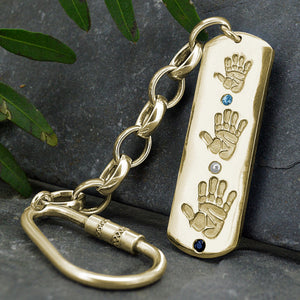 Large dog tag style long Pendant in solid gold with three children's handprints | Set with aquamarine, pearl and sapphire gemstones | Birthstones for March, June and September | Shown on a keyring with a chain | Personalised Gift | Sophia Alexander Fingerprint Jewellery | Handmade in Suffolk UK